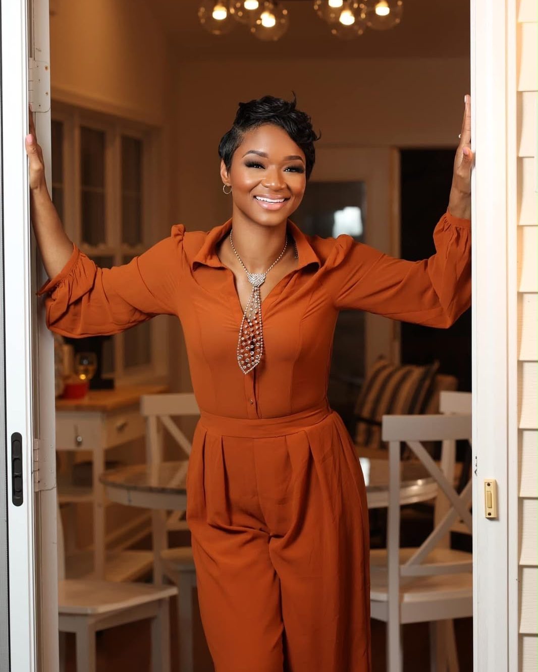 Brandy Tyson-Cummings smiling in an open doorway, arms spread in welcome