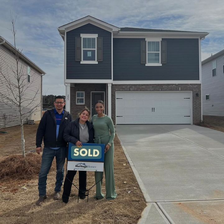 The Perez family with Brandy in front of their new home, holding a SOLD sign